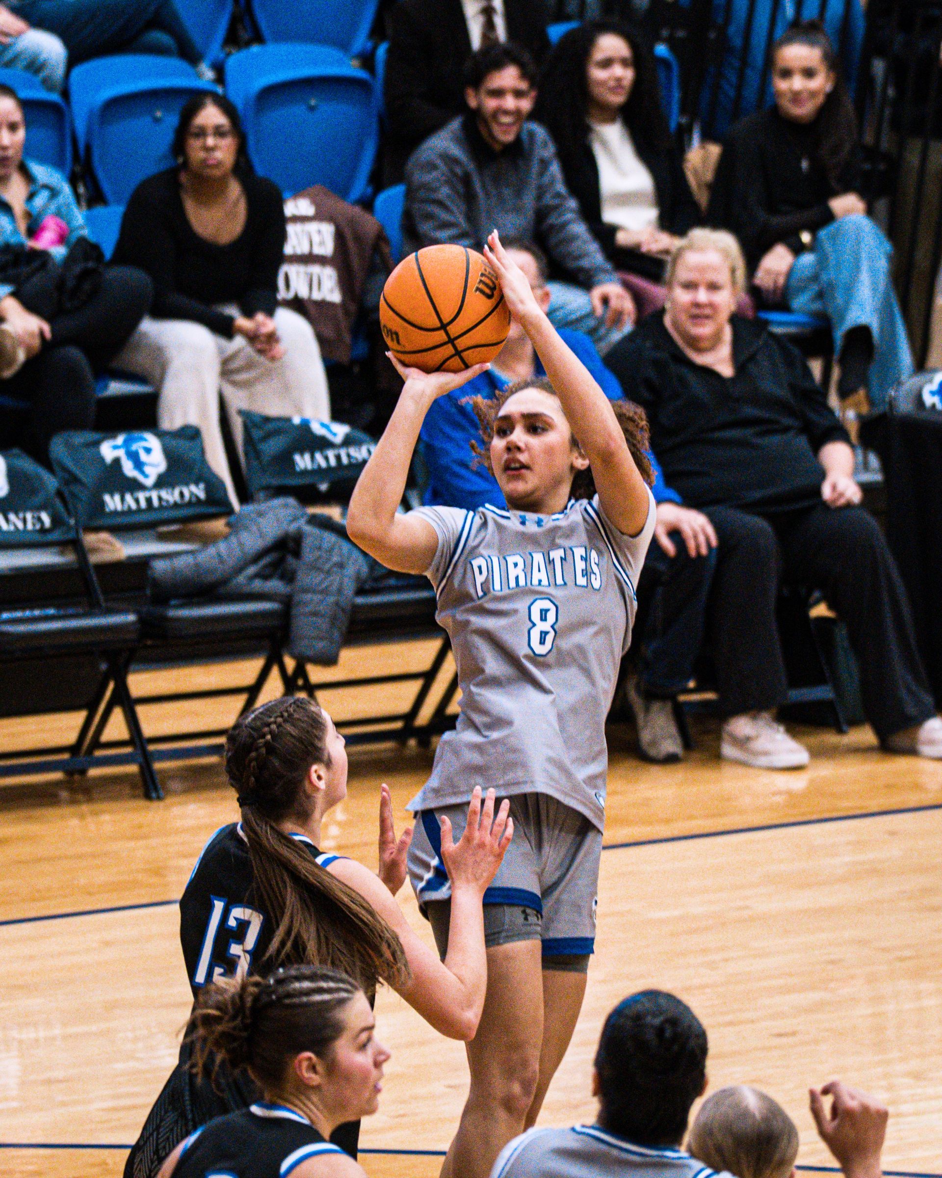 Basketball player in gray jersey shoots over a defender during an indoor game