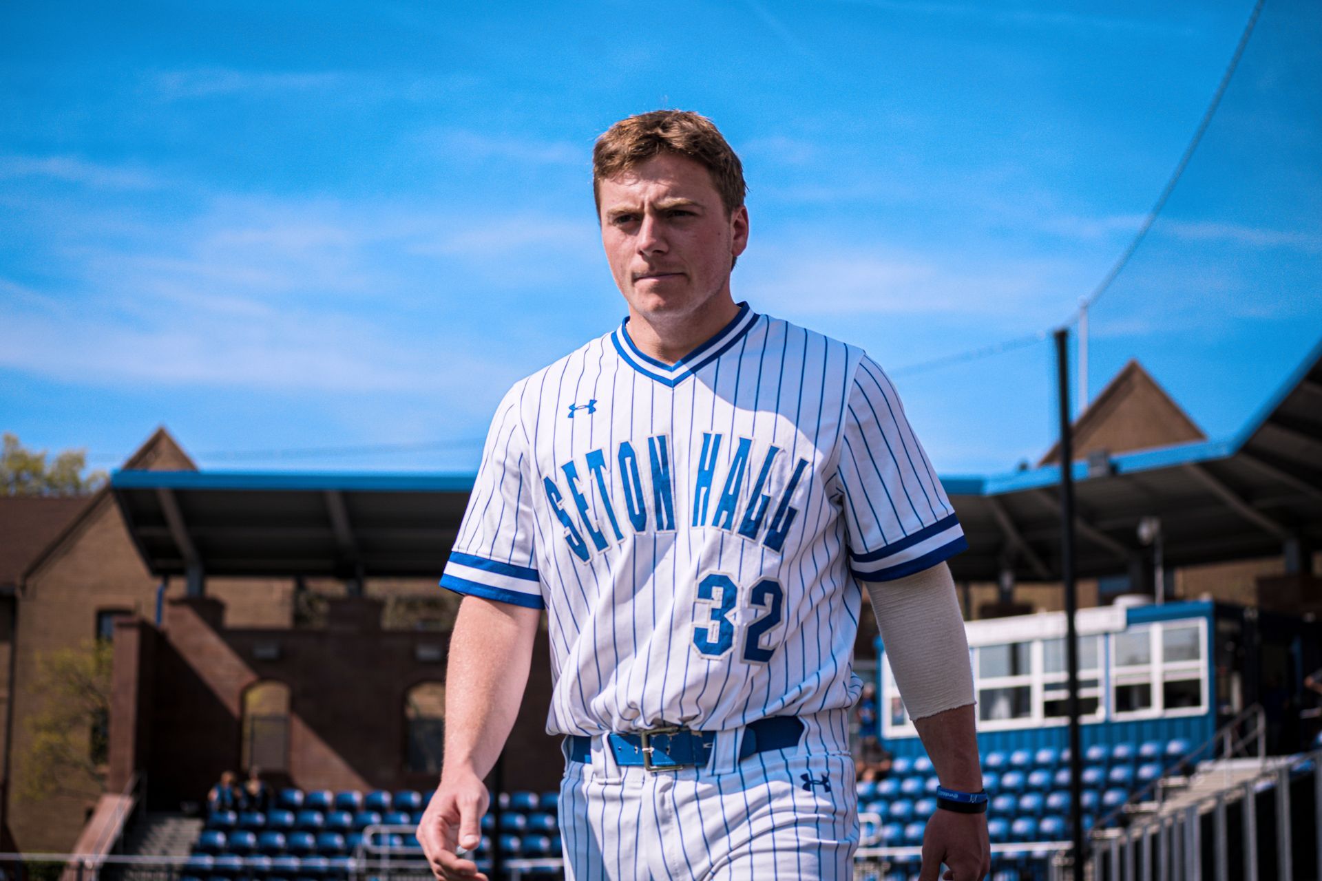 Baseball player in a white pinstriped uniform walking on the field under a blue sky