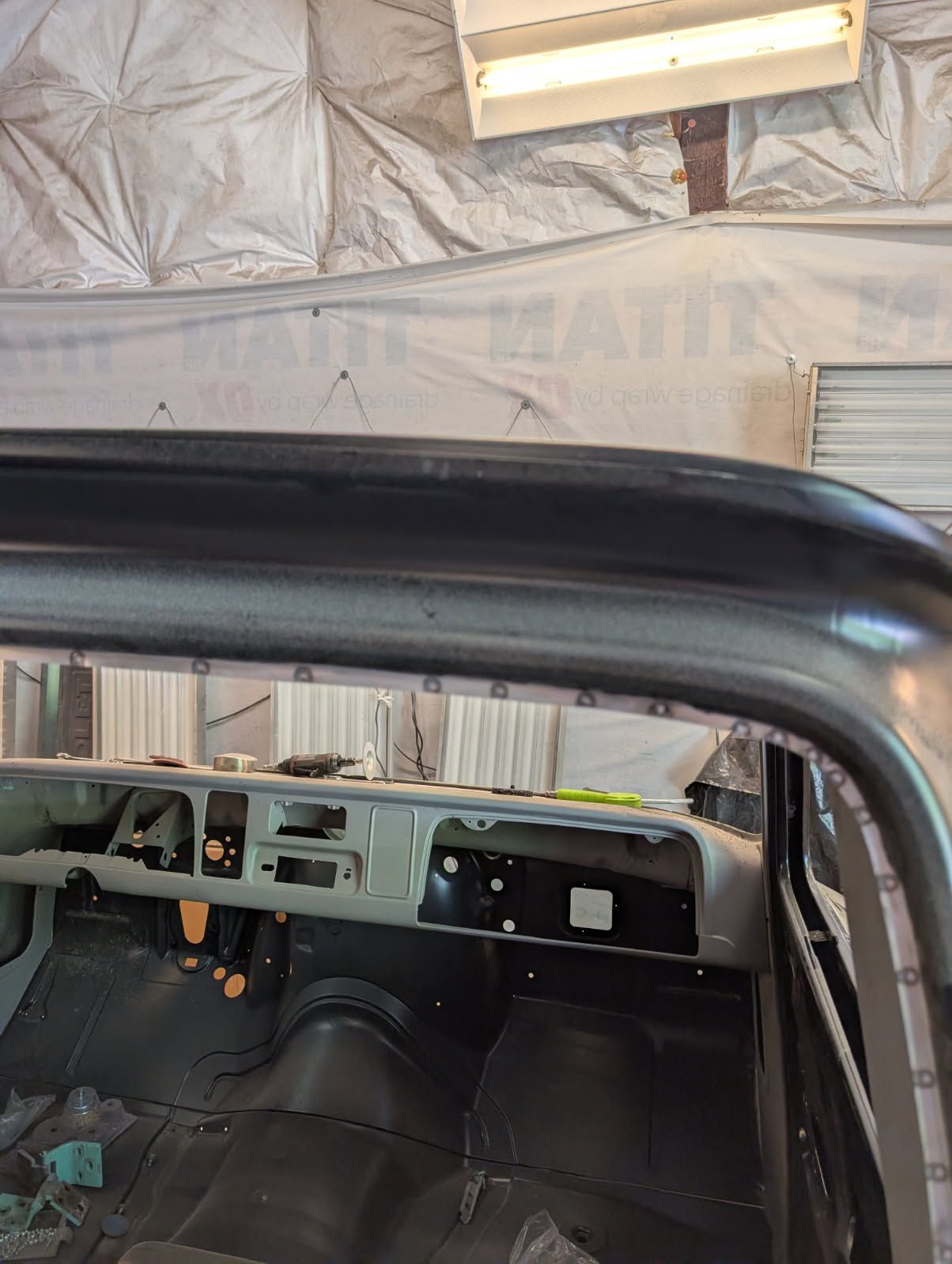 Classic car interior under restoration with exposed black seats and metal dashboard frame inside a workshop