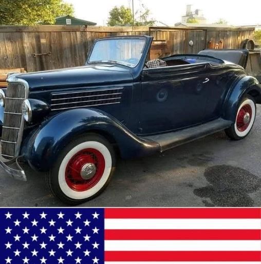 Dark blue vintage convertible with whitewall tires parked outdoors, with a U.S. flag graphic below.