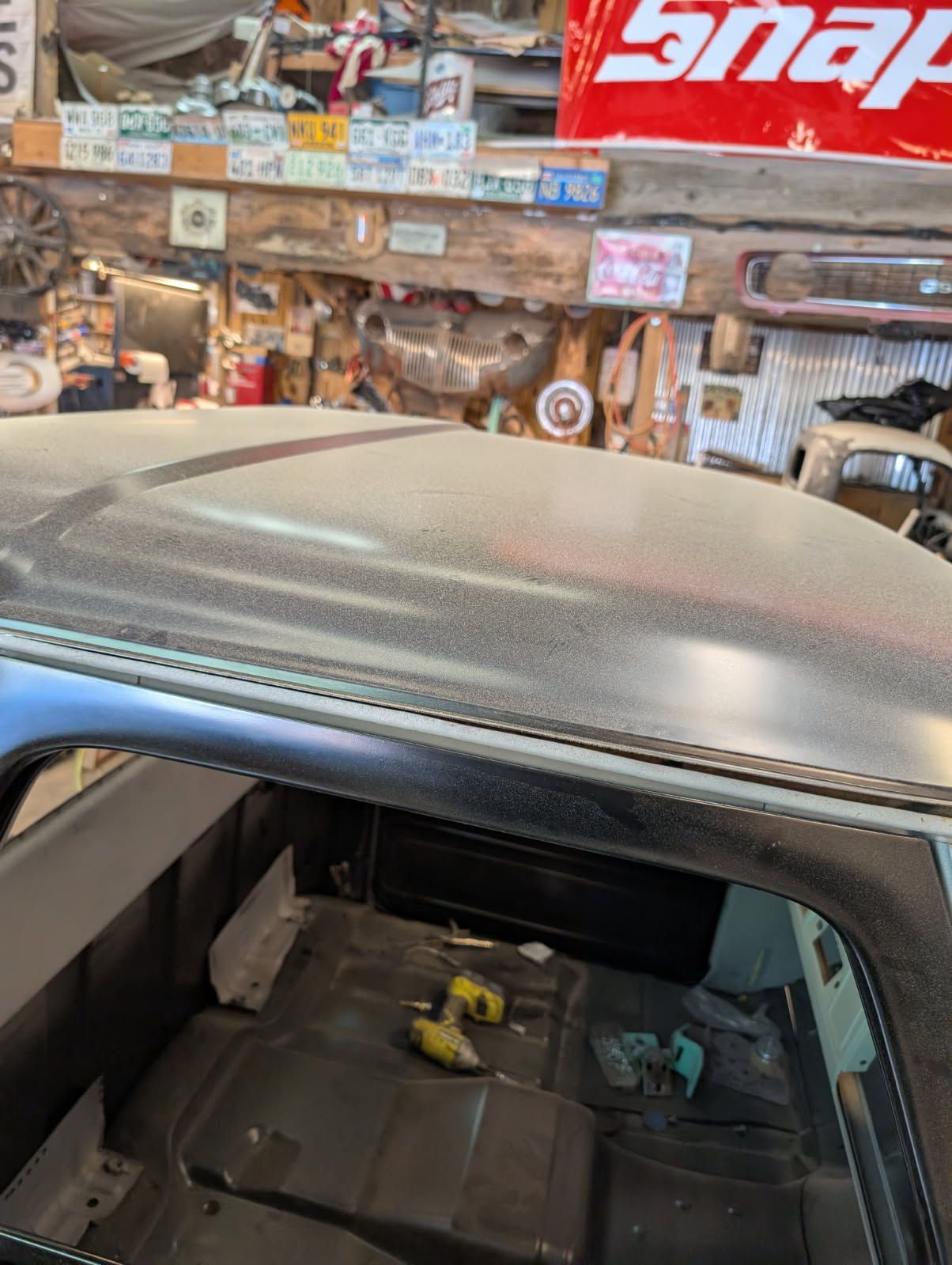 Dusty car roof in a cluttered garage with tools and a Snap-on sign in the background