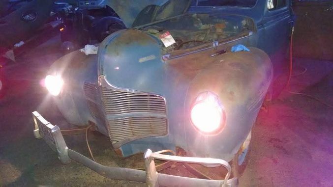 Vintage blue car front at night with bright headlights and chrome grille
