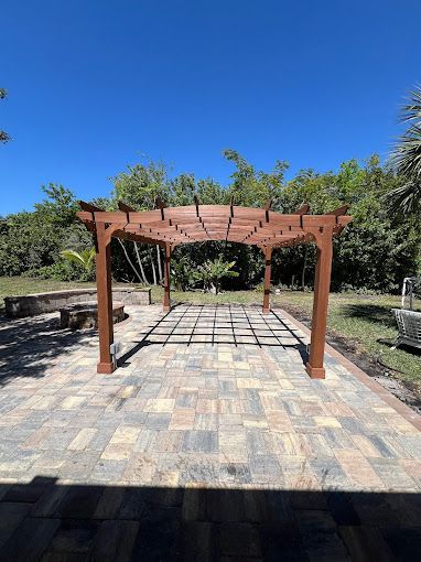 A wooden pergola is sitting on top of a brick patio.