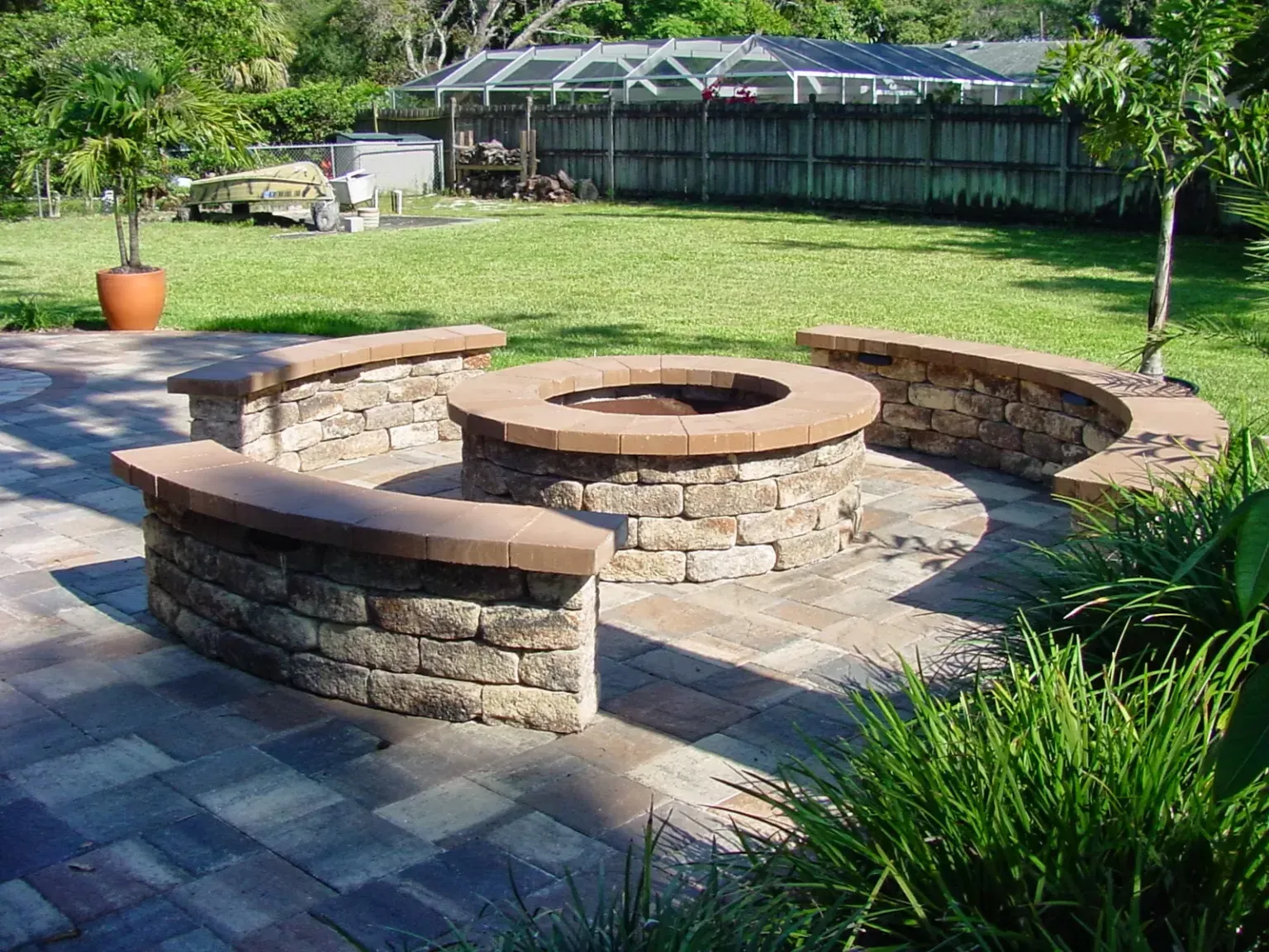A fire pit is surrounded by stone benches on a patio