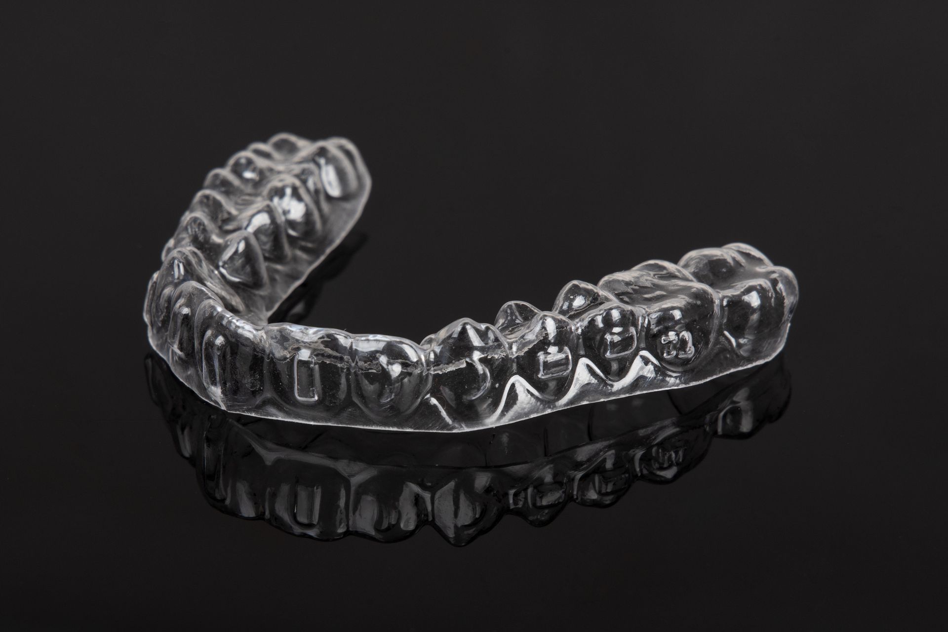 Clear aligners on a black background for an invisible, confident smile.