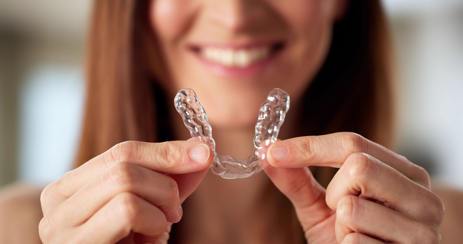 Dentist fitting a clear aligner night guard on a woman’s teeth for comfort and care.