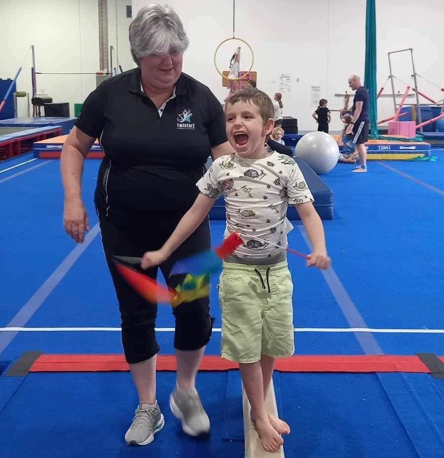 A woman is standing next to a young boy in a gym