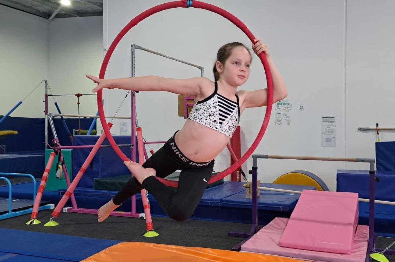 A young girl is doing aerial hoop exercises in a gym.