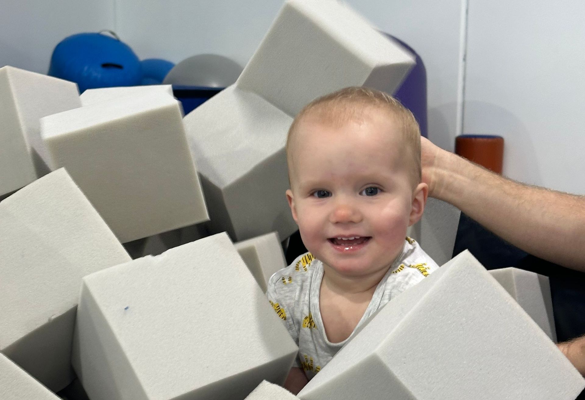 A baby is sitting in a pile of foam cubes.
