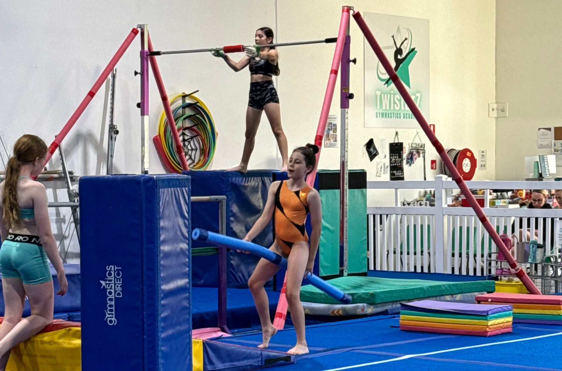 A group of young girls are practicing gymnastics in a gym.