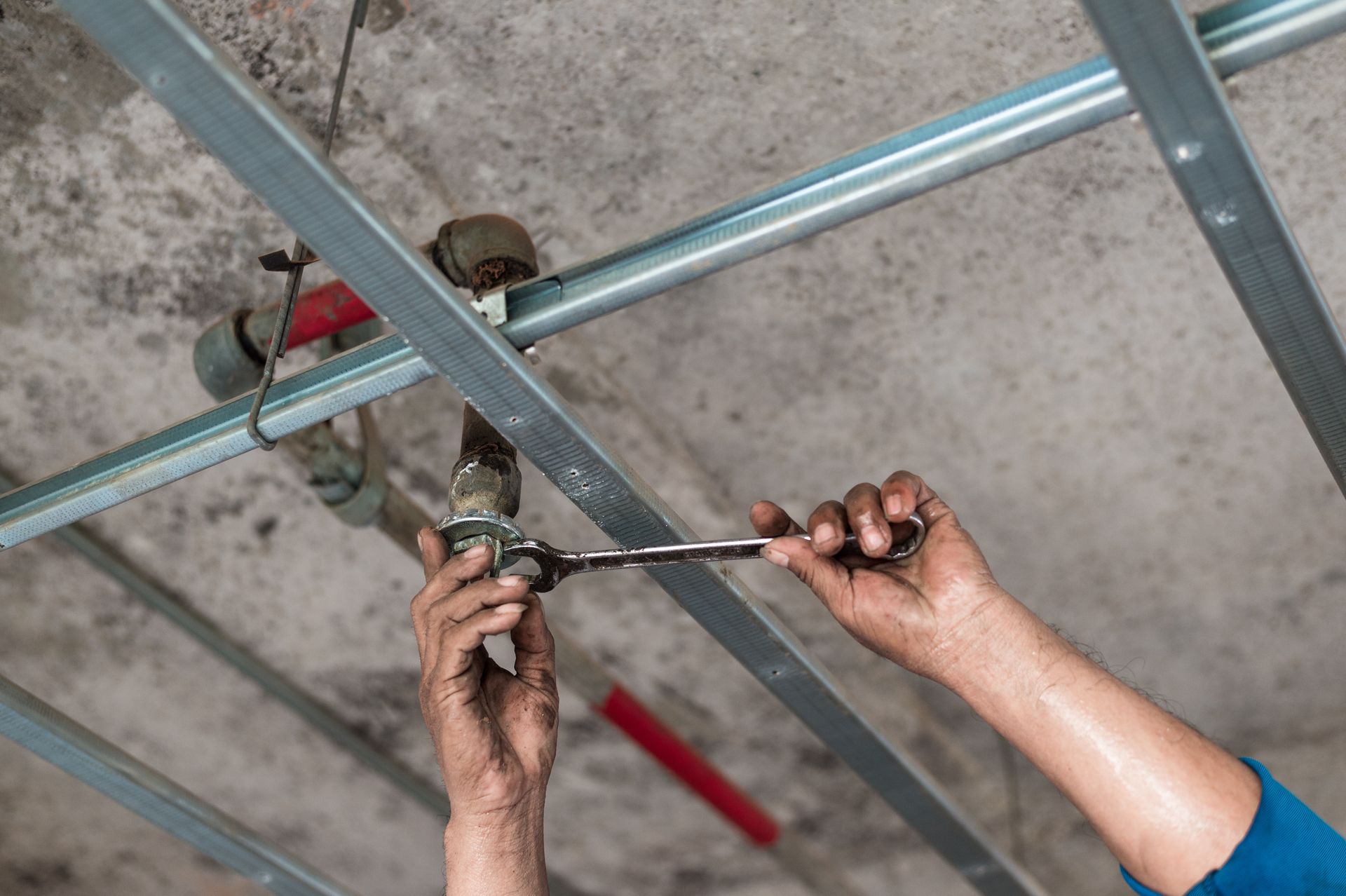 A technician is adjusting a ceiling pipe, showcasing fire sprinkler inspection services. A technician is adjusting a ceiling pipe, showcasing fire sprinkler inspection services.