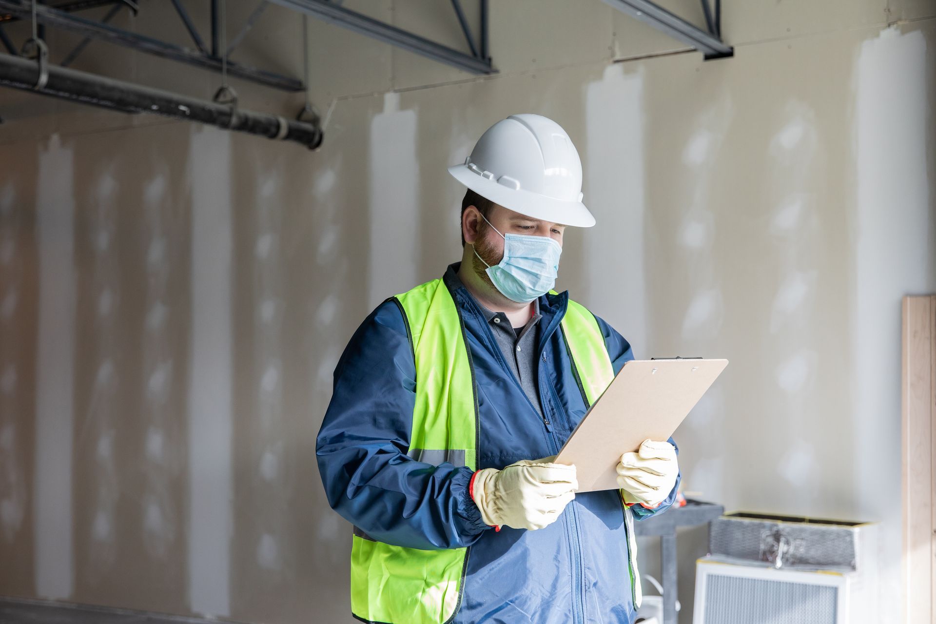 Sprinkler Head - Fire Sprinkler Services in Fort Wayne, IN A Construction Worker Wearing a Mask and Hard Hat is Looking at a Clipboard - Fire Sprinkler Services in Fort Wayne, IN
