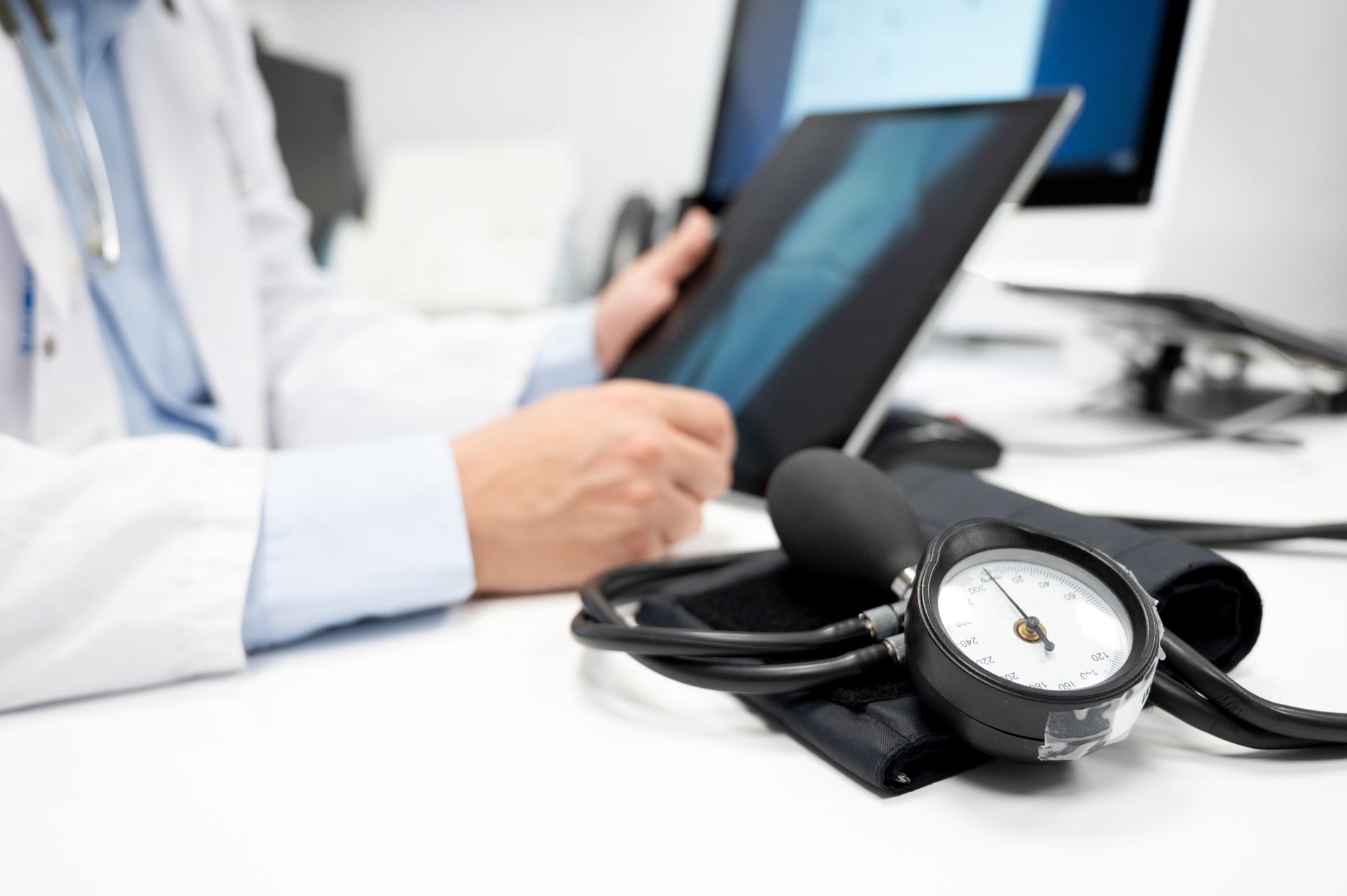 Medico con un tablet accanto a un misuratore di pressione sanguigna su una scrivania