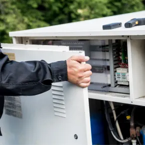 Apex Climate Control -  A man is opening a cabinet with a screwdriver in it.
