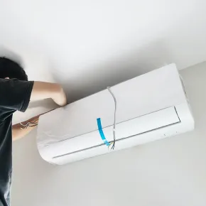 Apex Climate Control -  A man is installing an air conditioner on the ceiling.