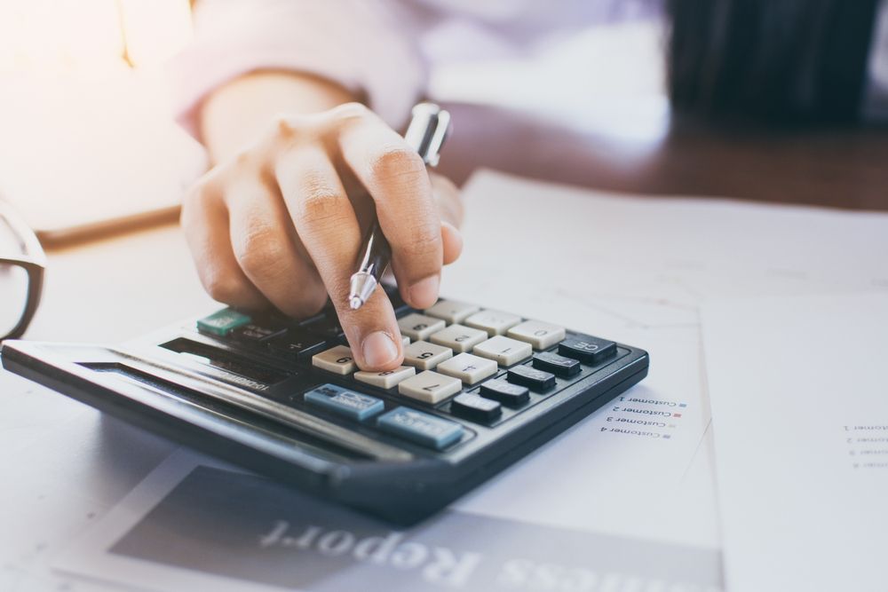 A Person Is Using A Calculator And Writing On A Piece Of Paper — Scott Kennedy's Landscape & Garden Supplies In Shaw, QLD