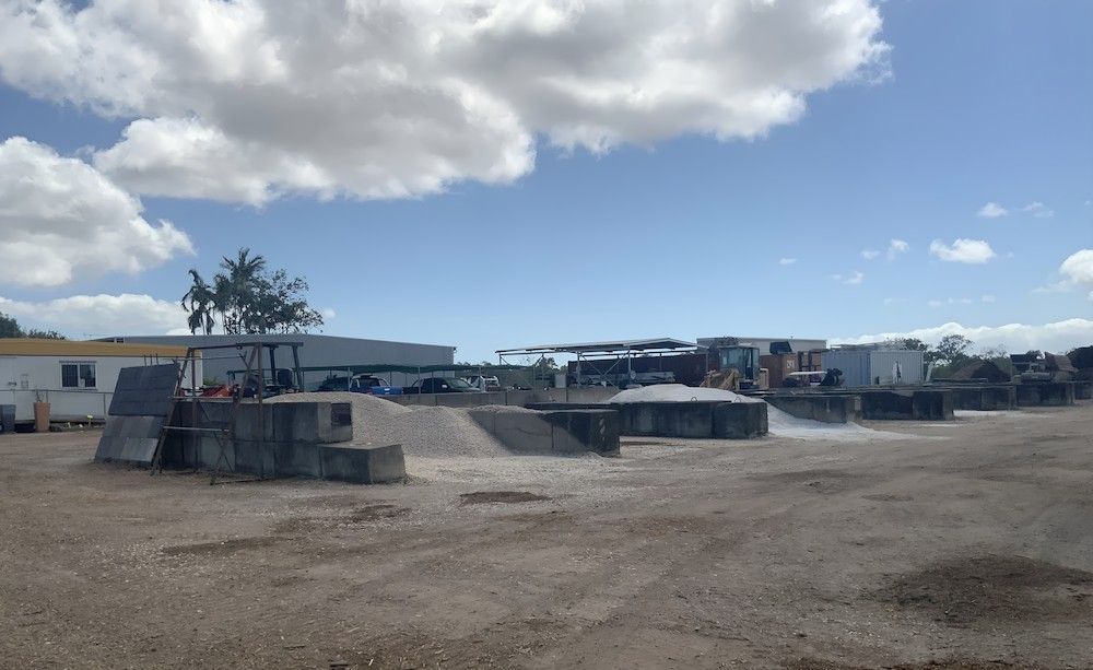 A Large Dirt Field With A Building In The Background — Scott Kennedy's Landscape & Garden Supplies In Shaw, QLD