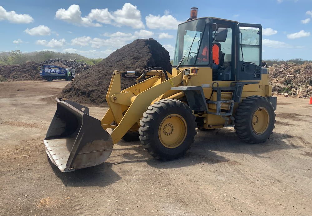 A Yellow Bulldozer Is Parked In A Dirt — Scott Kennedy's Landscape & Garden Supplies In Shaw, QLD