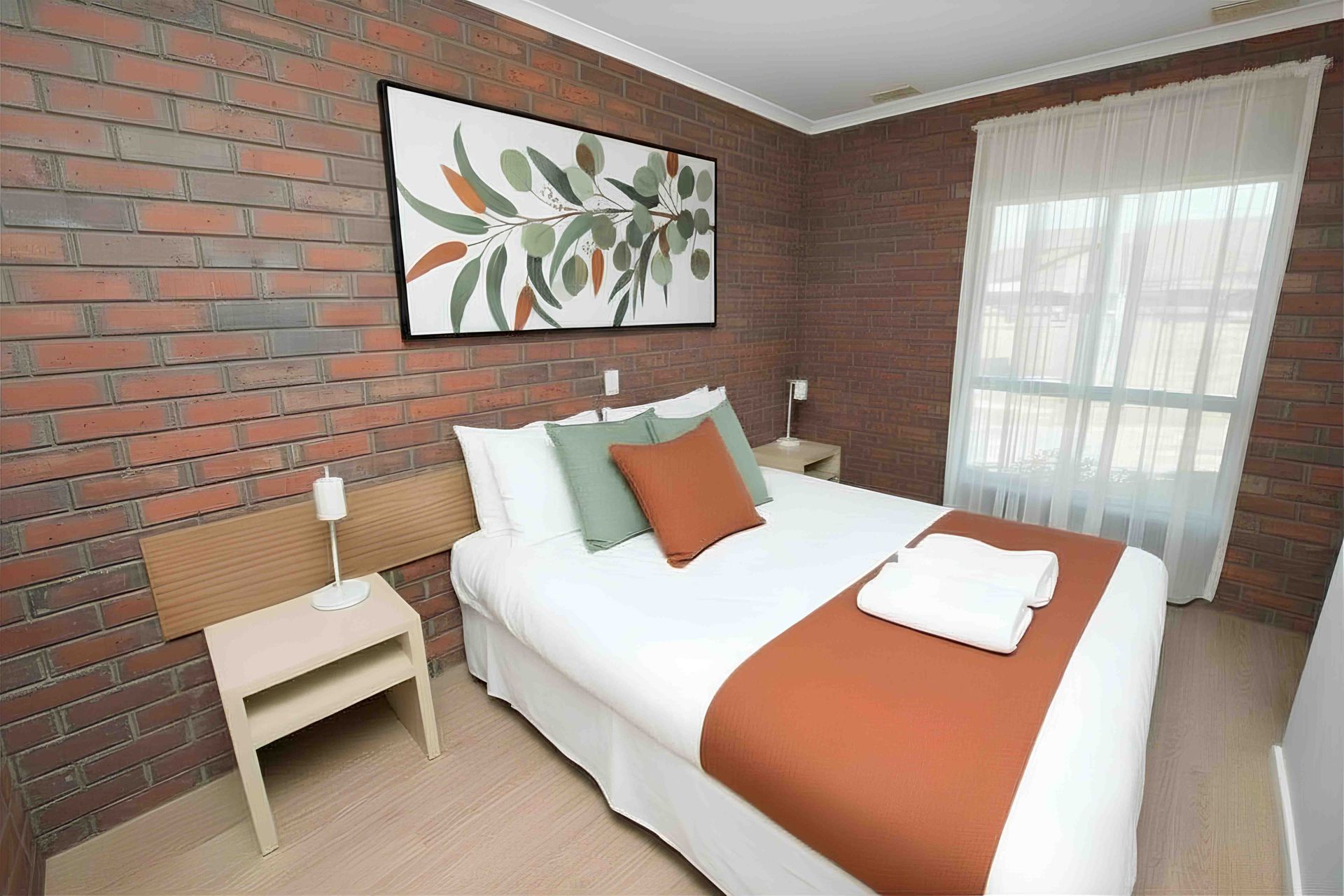 Bedroom with a bed, window with curtains, closet, and carpet. White walls, bedspread with brown accents.
