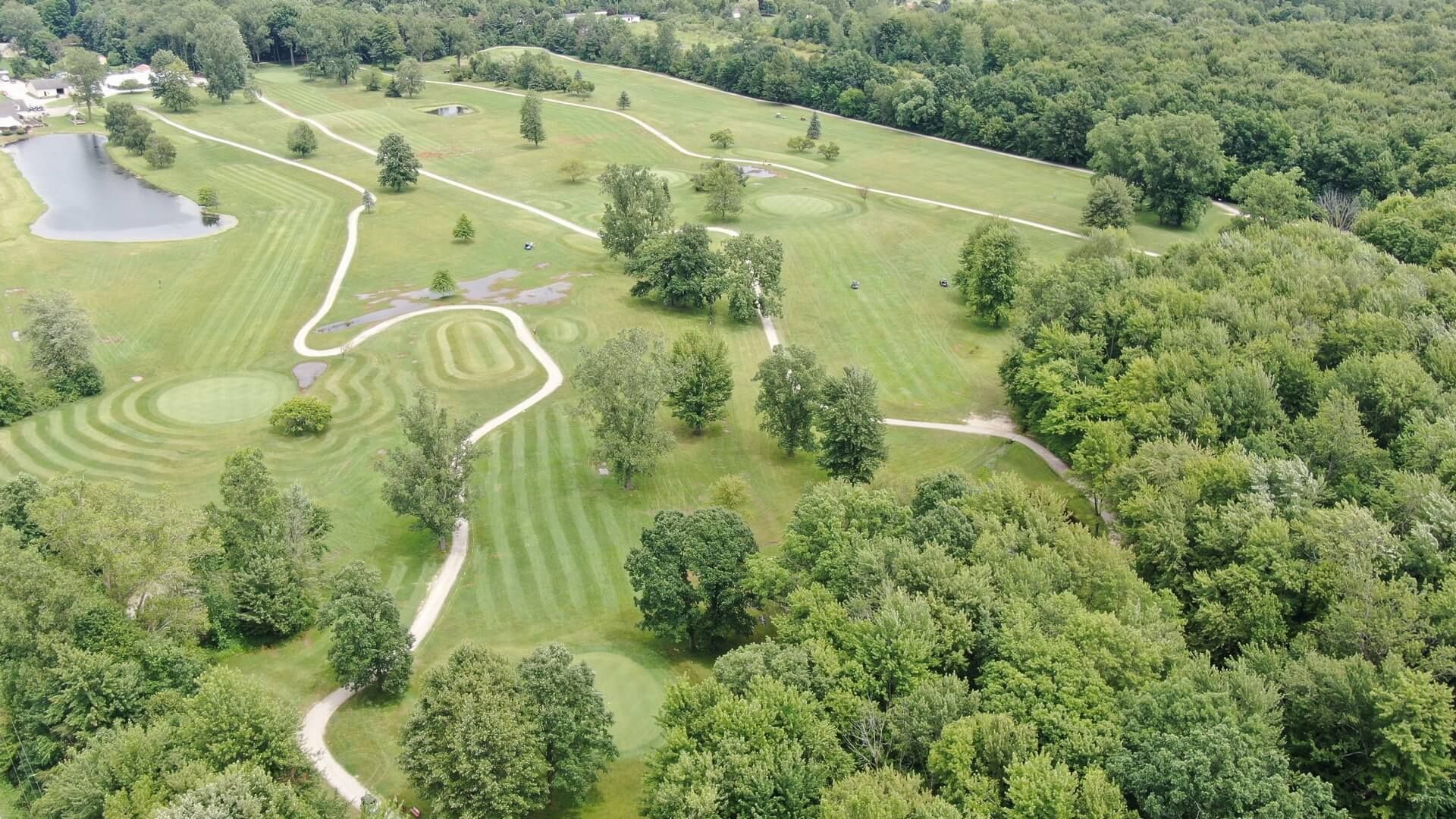 An aerial view of a golf course surrounded by trees and grass.