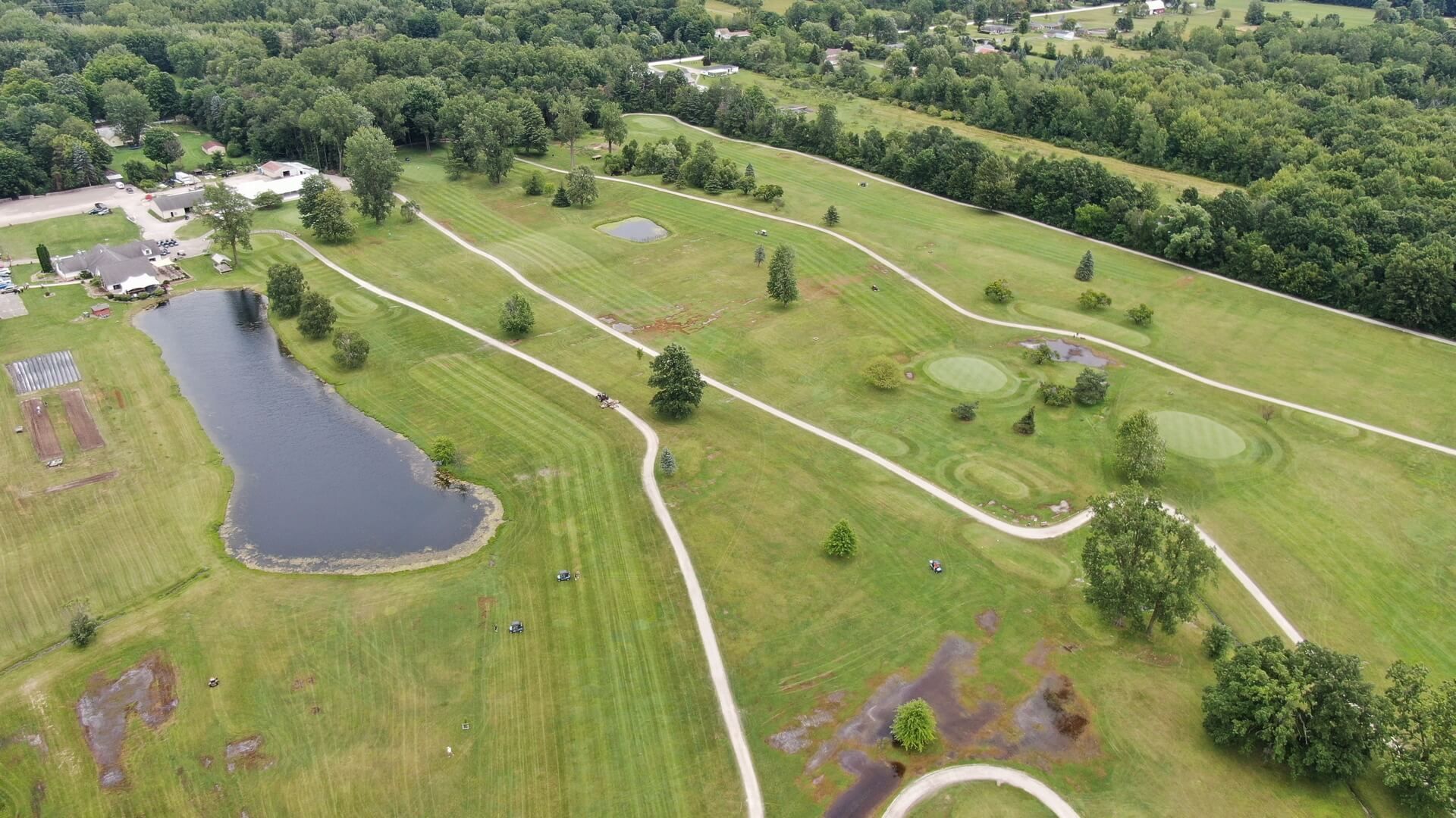 An aerial view of a golf course surrounded by trees and grass.