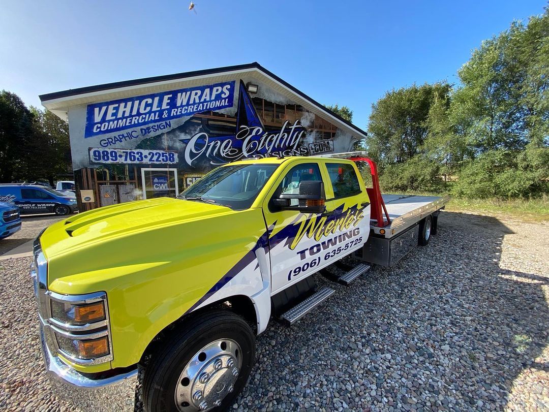 A yellow tow truck is parked in front of a building.