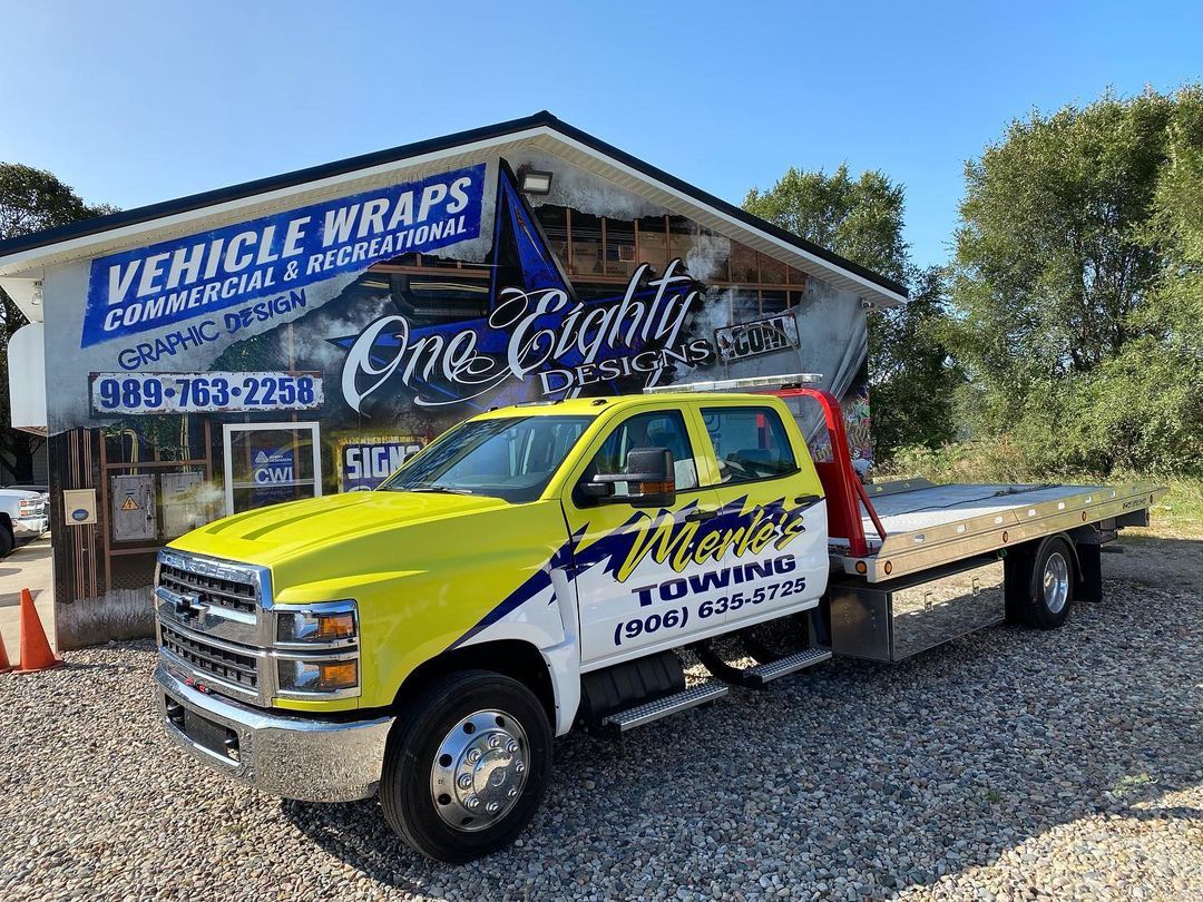 A yellow tow truck is parked in front of a building.