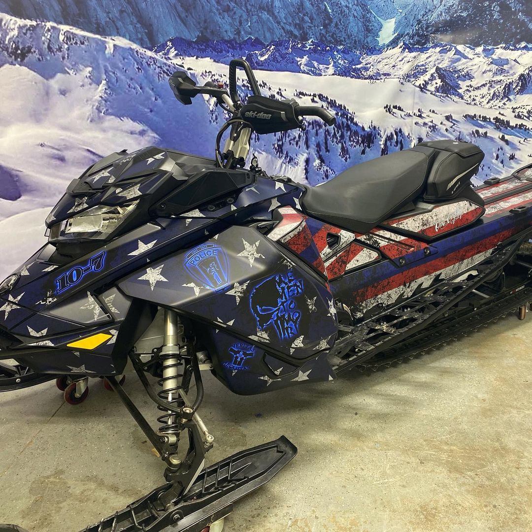 A snowmobile is parked in front of a snowy mountain.