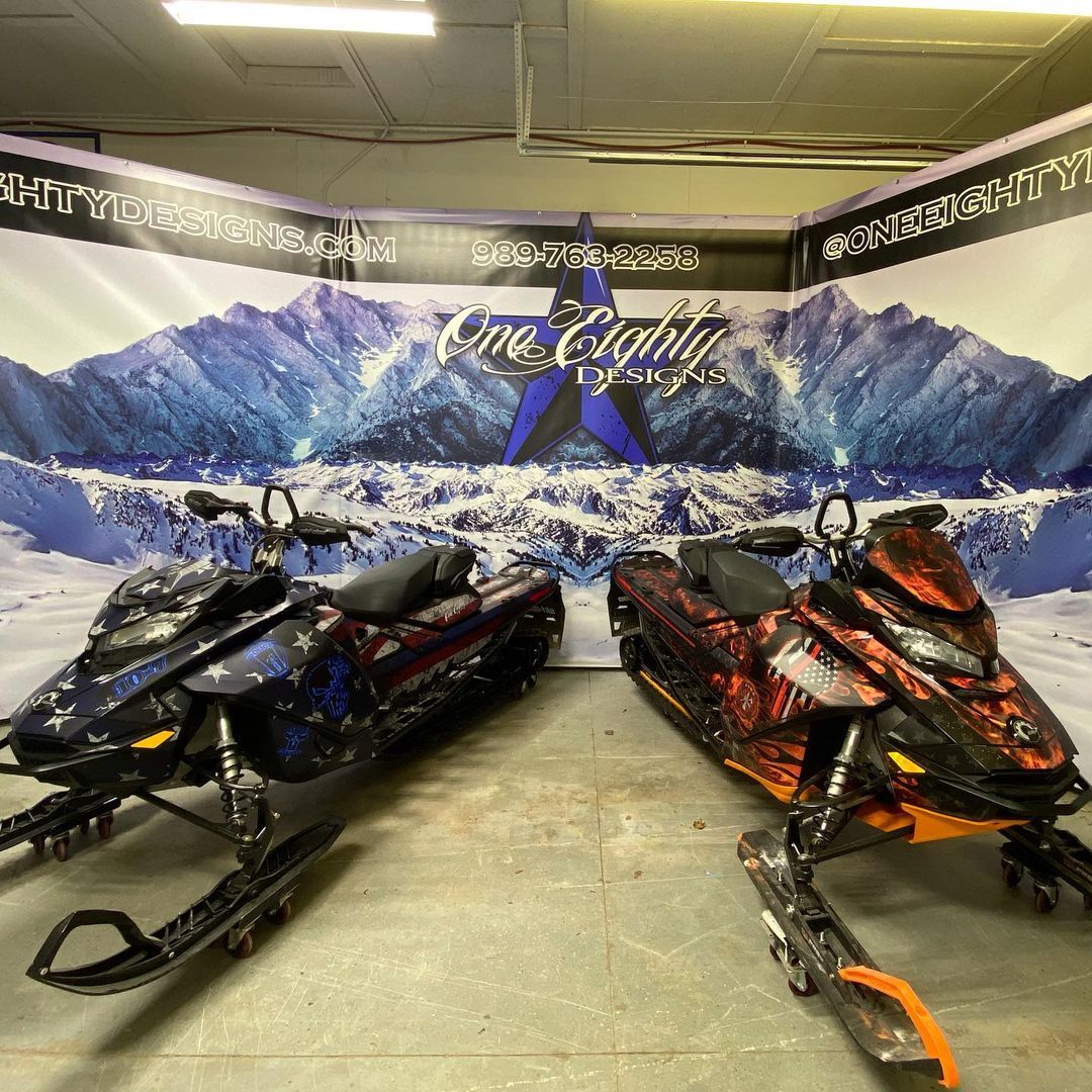 Two snowmobiles are parked next to each other in a room.