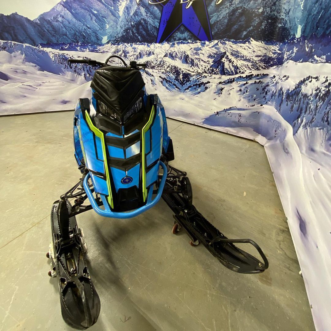 A blue snowmobile is sitting on a concrete floor