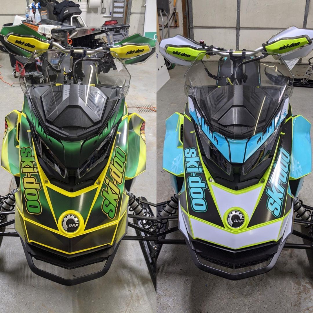 Two ski doo snowmobiles are sitting next to each other in a garage.