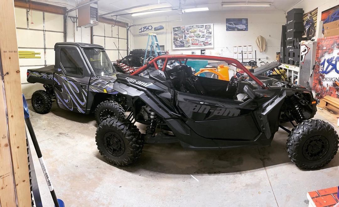 Two atvs are parked in a garage next to each other.