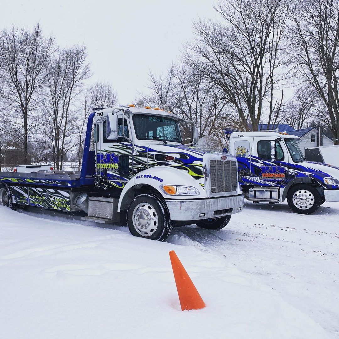 Two tow trucks are parked next to each other in the snow.