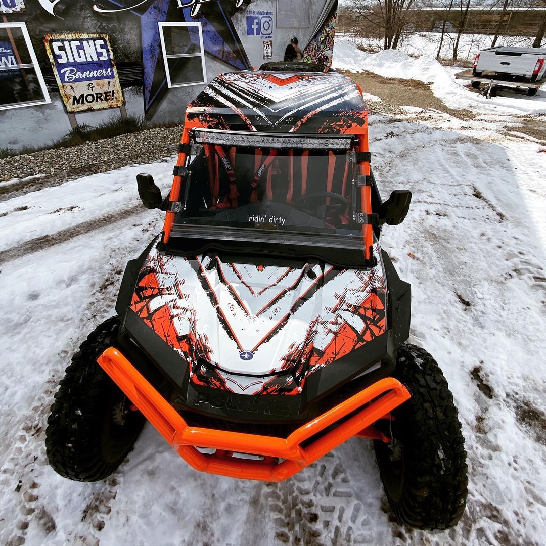 A black and orange atv is parked in the snow.