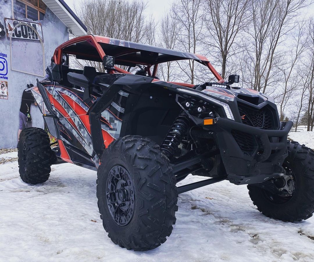 A red and black atv is parked in the snow in front of a building.