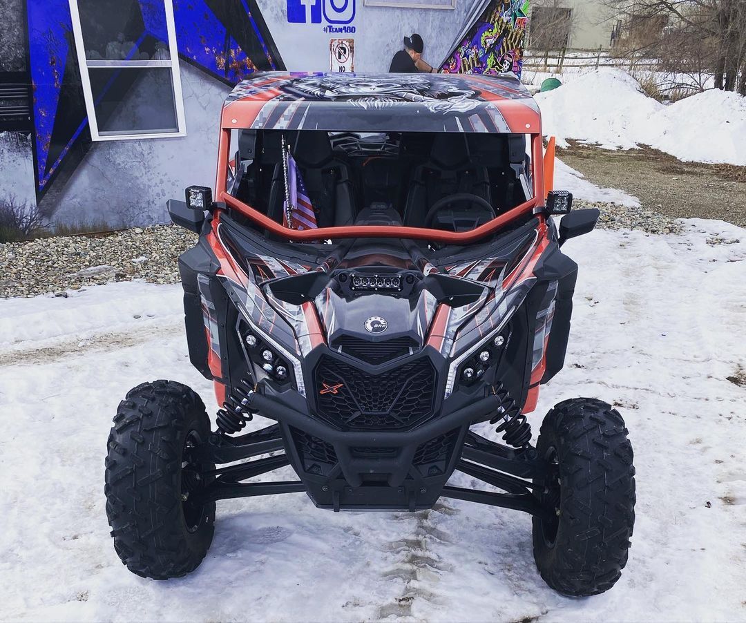 A red and black atv is parked in the snow in front of a building.