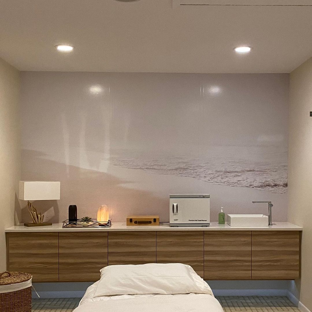 There is a bed in the middle of the room with a picture on the wall behind it.