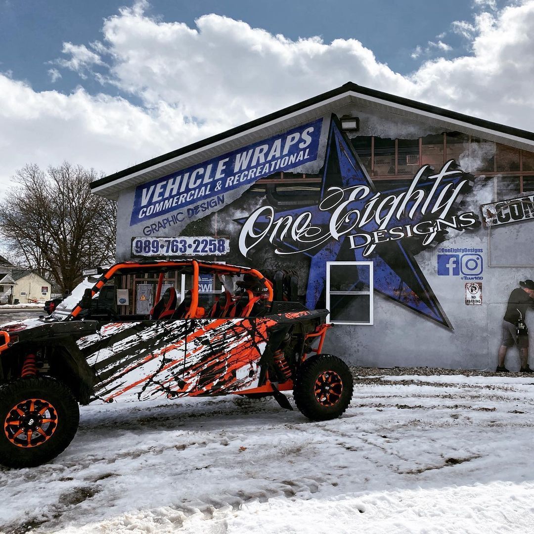A vehicle wrap is sitting in front of a building in the snow.
