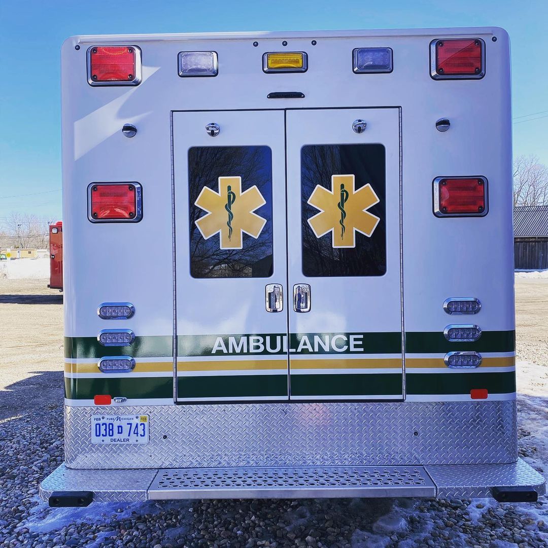 A white and green ambulance with the word ambulance on the back