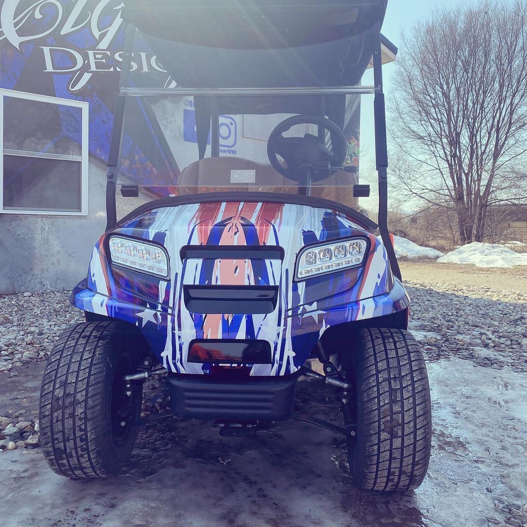 A blue and white golf cart is parked in the snow