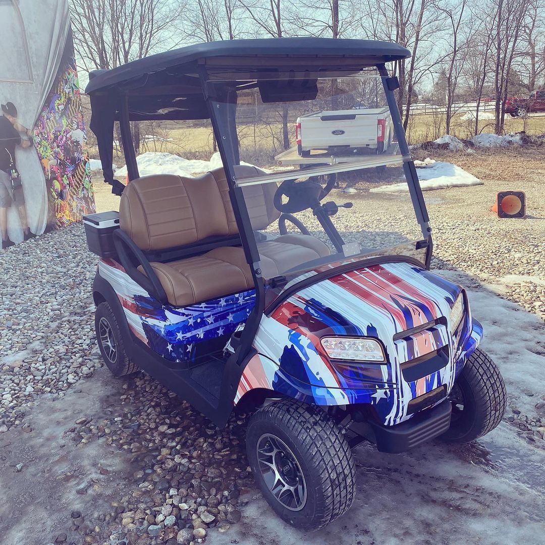 A golf cart with the american flag painted on it is parked in the snow.