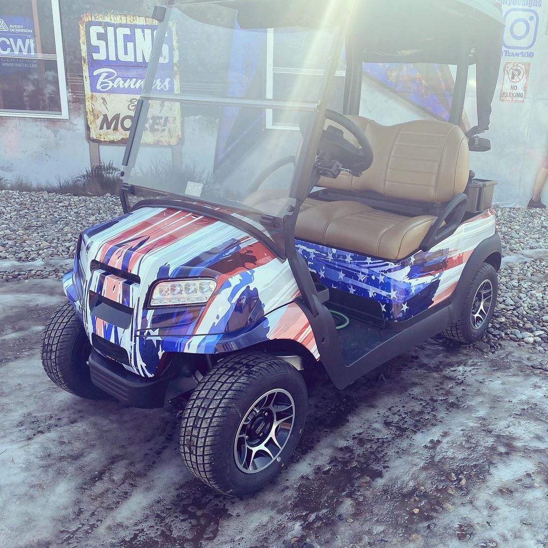 A golf cart with an american flag wrap is parked in the snow.