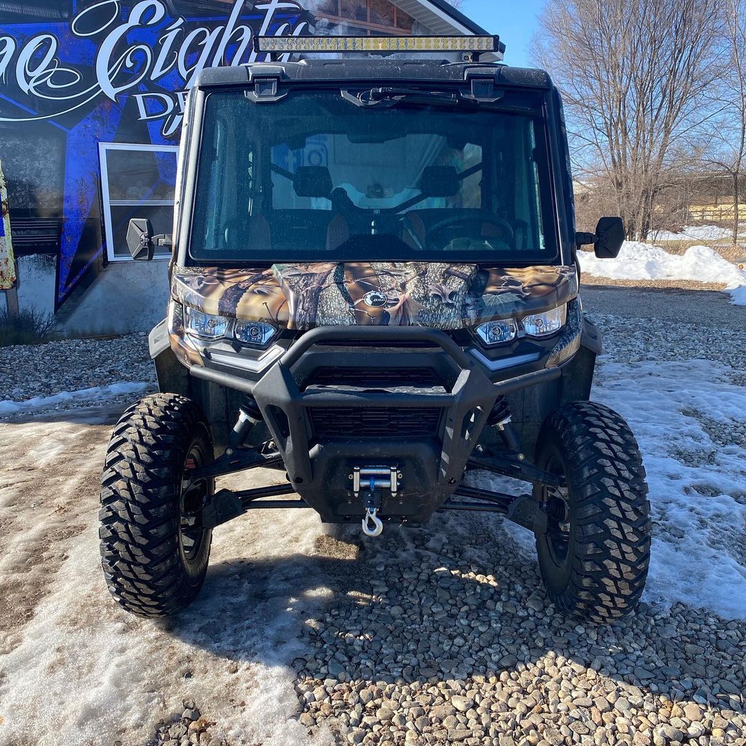 A polaris ranger is parked in the snow in front of a building.