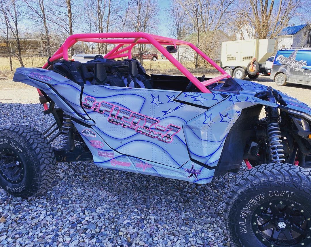A blue and pink atv is parked in a gravel lot.
