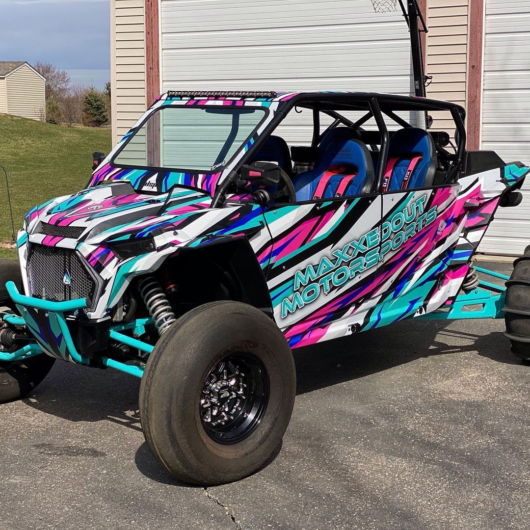 A colorful atv is parked in front of a garage.