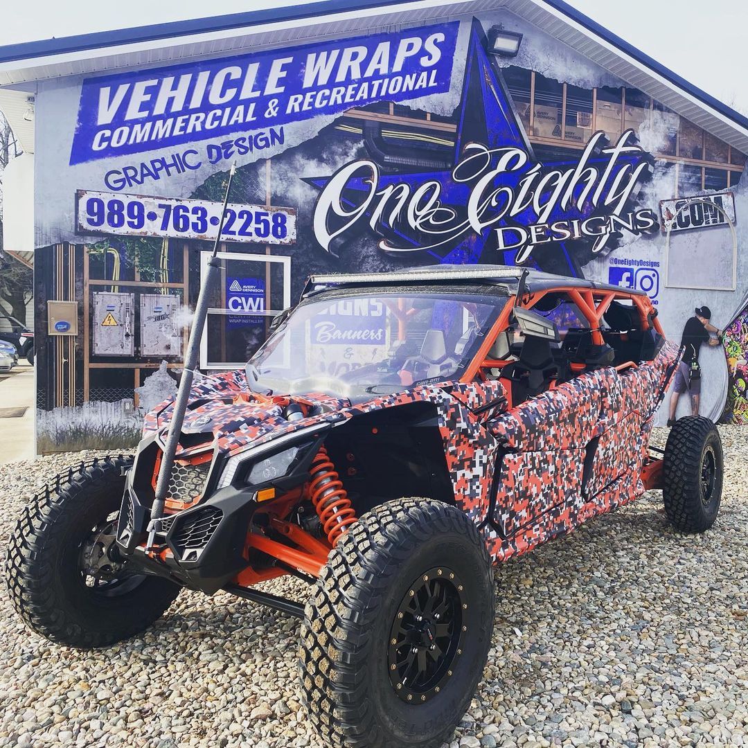 A red and orange atv is parked in front of a building.