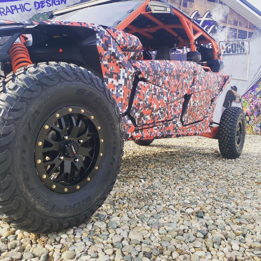 A red camo atv is parked on gravel in front of a building that says graphic design
