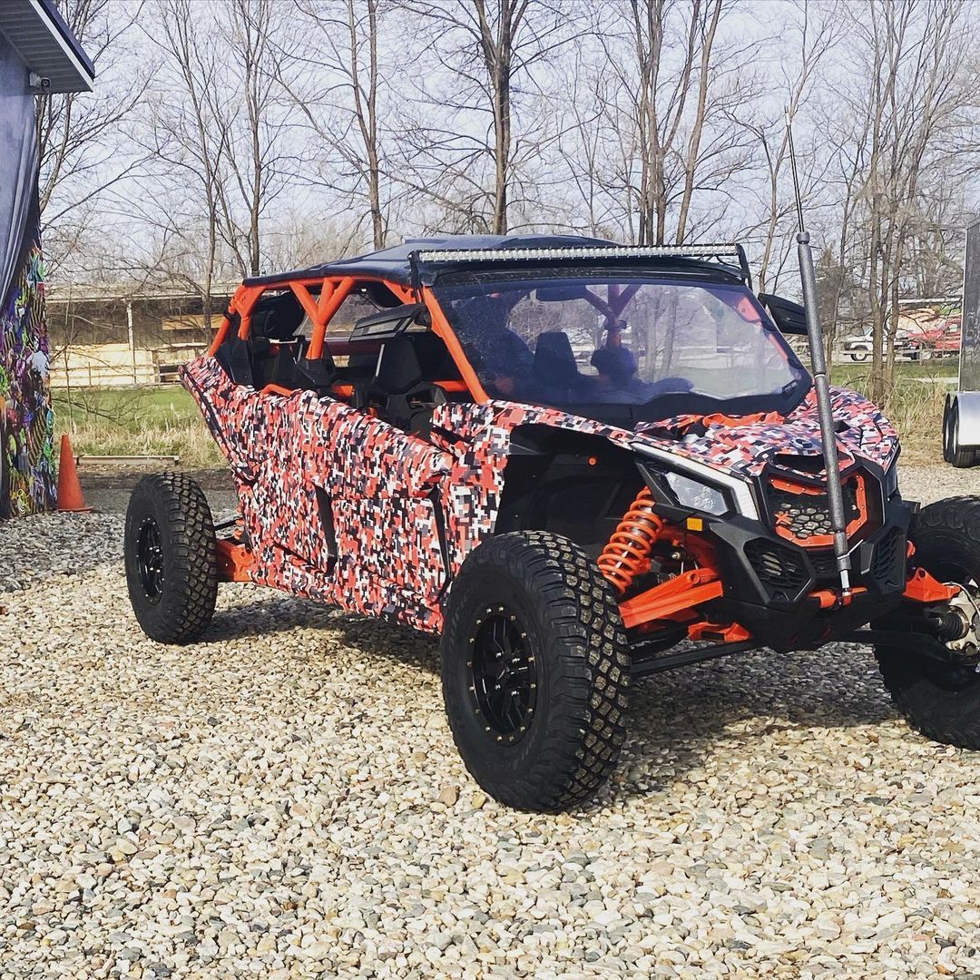 A red and orange atv is parked in a gravel lot.