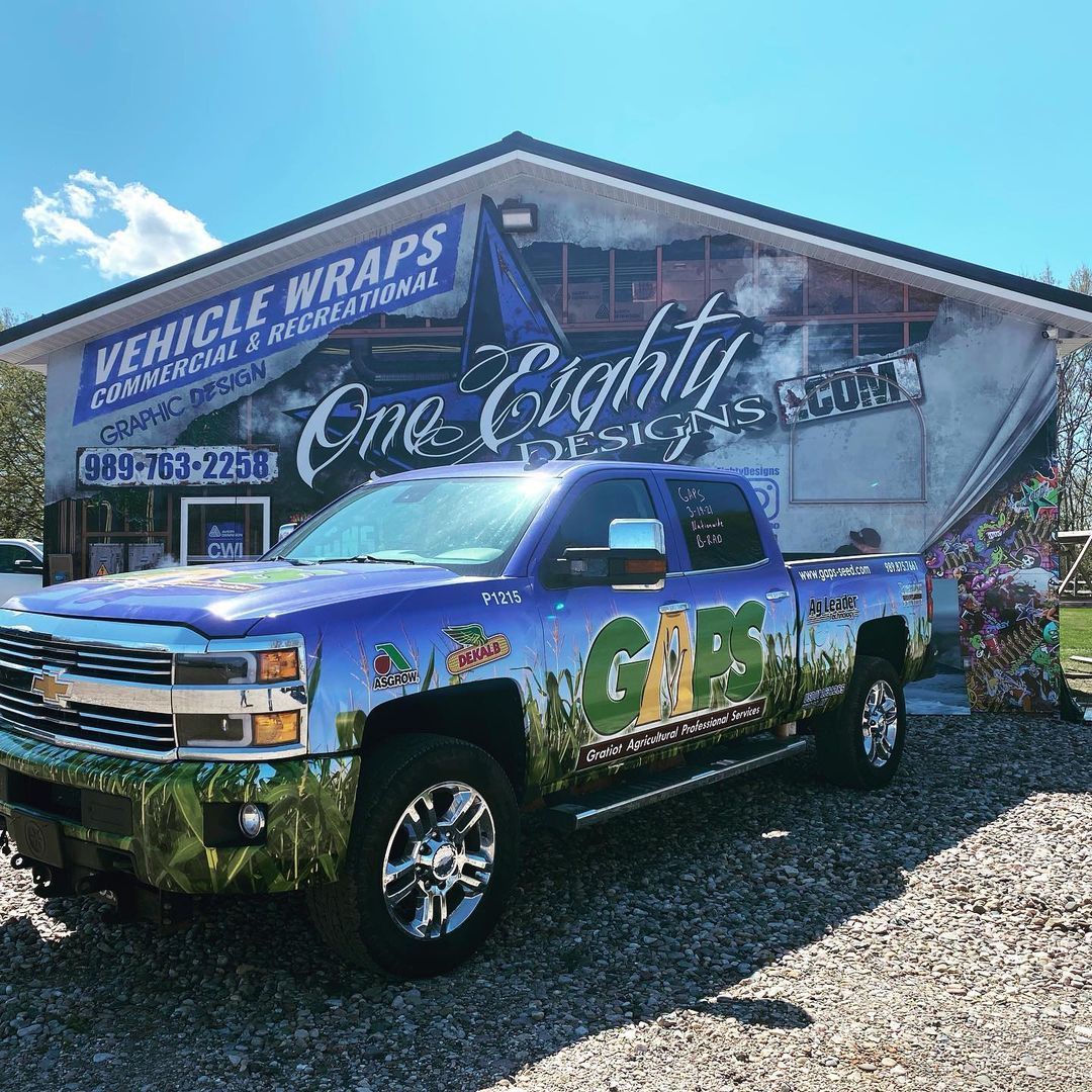 A purple truck is parked in front of a building that says vehicle wraps