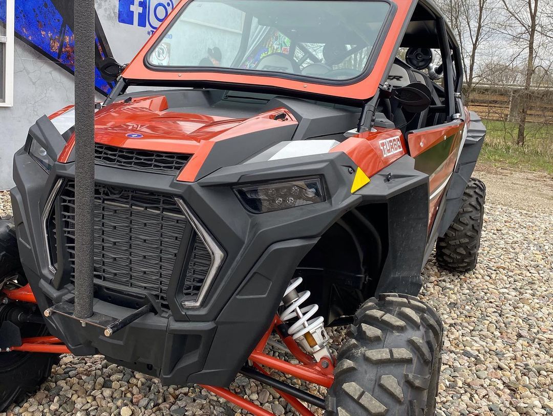 A red and black atv is parked in a gravel lot.